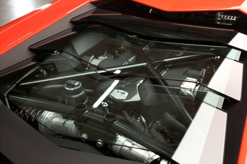 Мощный 12-цилиндровый двигатель смонтирован за спинками сидений и укрыт прозрачной панелью (опция).