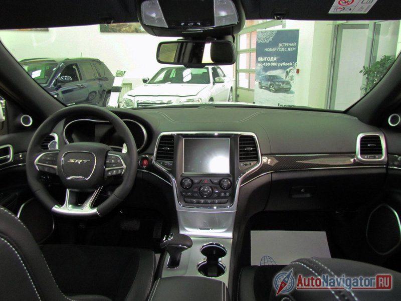 В салоне выделяются руль с лепестками и надписью SRT, красная кнопка пуска двигателя, большой дисплей коммуникационной системы и селектор новой восьмиступенчатой АКПП
