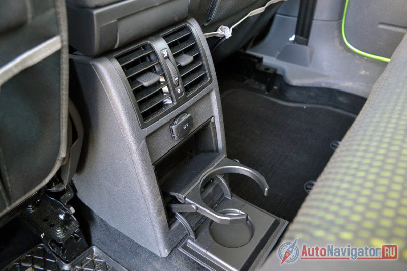 Поскольку сзади три полноценных места, подлокотника и лючка для длинномеров нет. Чтобы хоть как-то компенсировать их отсутствие, на центральном тоннеле расположили один большой универсальный подстаканник. Тут же есть отдельная розетка для зарядки гаджетов, например. А еще выше – дефлекторы обдува