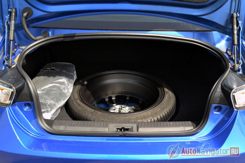 Запаска полноразмерная. Но так как машина очень низкая, под пол ее убрать не удалось, как и прикрыть, и она топорщится. Объем багажника всего 243 литра. Для нескольких сумок места хватит, а остальное можно кинуть на заднее сиденье