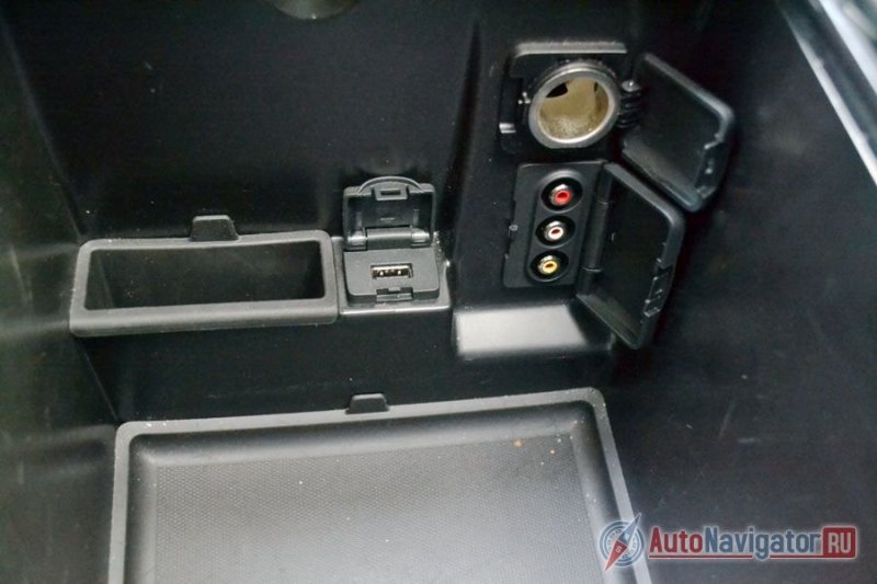 В боксе под подлокотником разъемы для подключения аудио- и видеоустройств и розетка на 12V